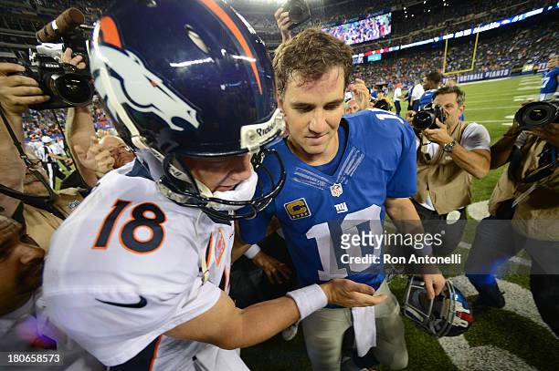 Quarterback Peyton Manning of the Denver Broncos and brother quarterback Eli Manning of the New York Giants shake hands at the end of the Denver...