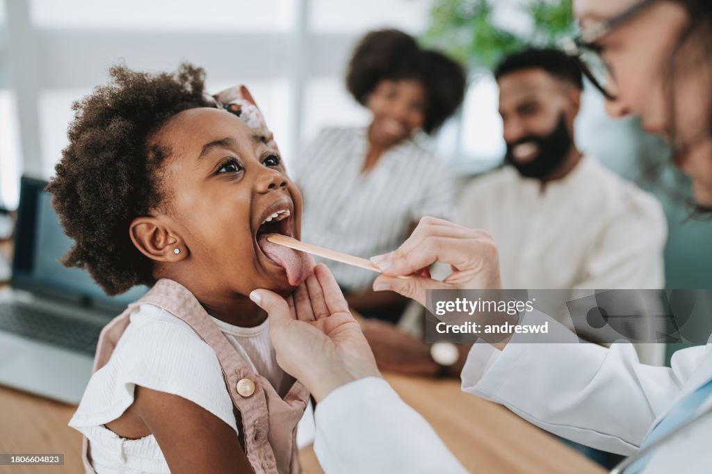 Pediatrician analyzing throat infection with tongue stick