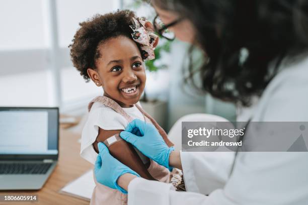 doctor putting a bandage on the child's arm after the vaccine - kid punching stock pictures, royalty-free photos & images