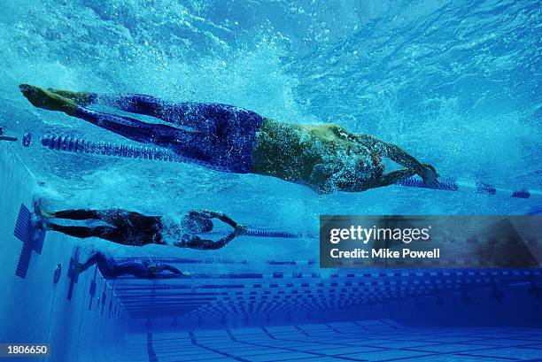 Three female swimmes performing racing turns in competition, underwater view.