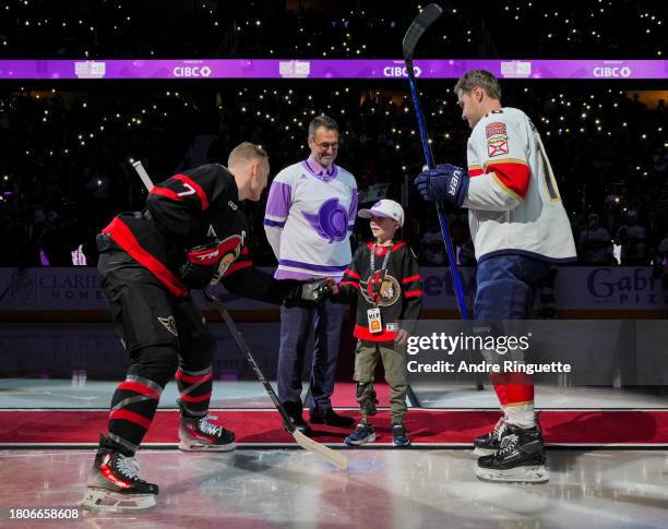 Brady Tkachuk of the Ottawa Senators gives the puck to Parker McDonald after a ceremonial face-off on Hockey Fights Cancer night as Ottawa Senators...