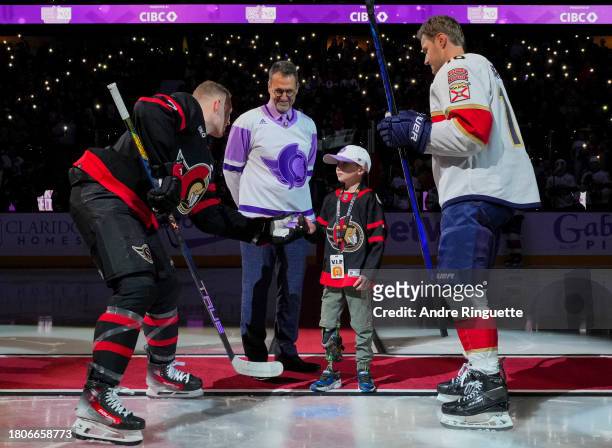 Brady Tkachuk of the Ottawa Senators gives the puck to Parker McDonald after a ceremonial face-off on Hockey Fights Cancer night as Ottawa Senators...