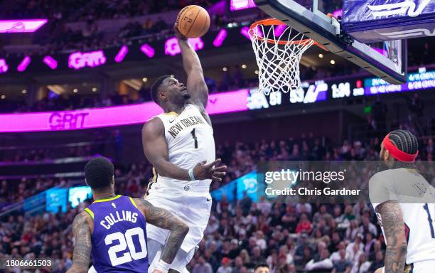 Zion Williamson of the New Orleans Pelicans dunks the ball next to John Collins of the Utah Jazz during the first half of the game at the Delta...