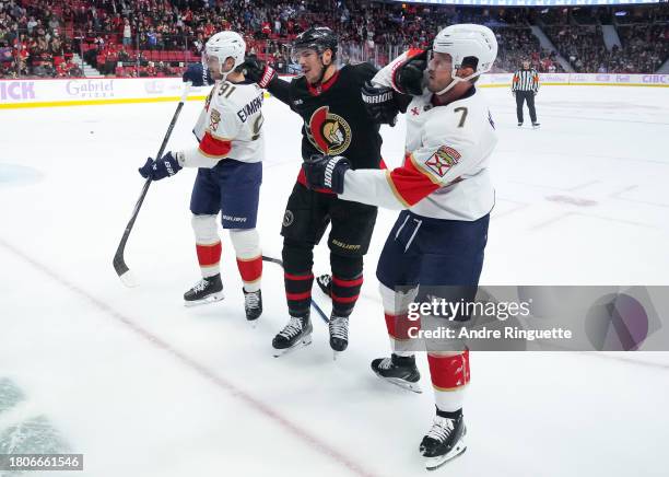 Travis Hamonic of the Ottawa Senators pushes and shoves with Dmitry Kulikov and Oliver Ekman-Larsson of the Florida Panthers during a scrum during...