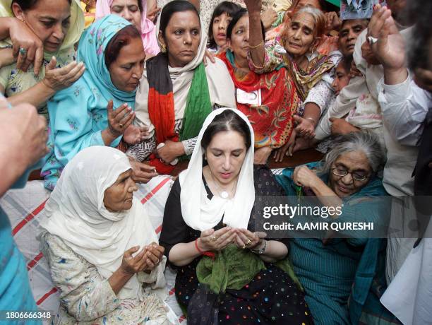 Former Pakistani prime minister Benazir Bhutto prays with the family of one of the victim of the 18 October suicide attacks in Karachi, during her...