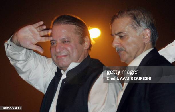 Former Pakistani prime minister Nawaz Sharif is watched by his brother Shahbaz Sharif as he salutes his supporters outside the Allama Iqbal...