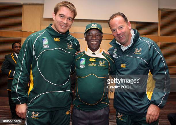 South African President Thabo Mbeki , wearing a rugby union national team jersey, hugs captain John Smit and coach Jake White during a meeting ahead...