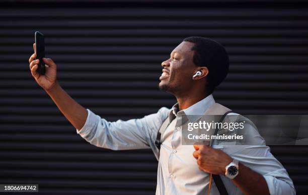 portrait of a happy businessman having an online meeting on his mobile phone outdoors - in ear headphones stock pictures, royalty-free photos & images