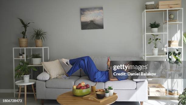 latin female gp relaxes on sofa at home with her phone. - life balance stock pictures, royalty-free photos & images