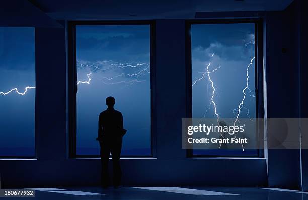 man standing in window during storm. - storm fotografías e imágenes de stock