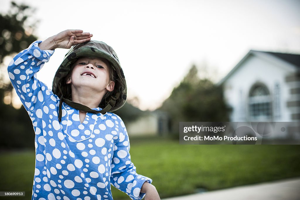 Young girl in army helmet a saluting