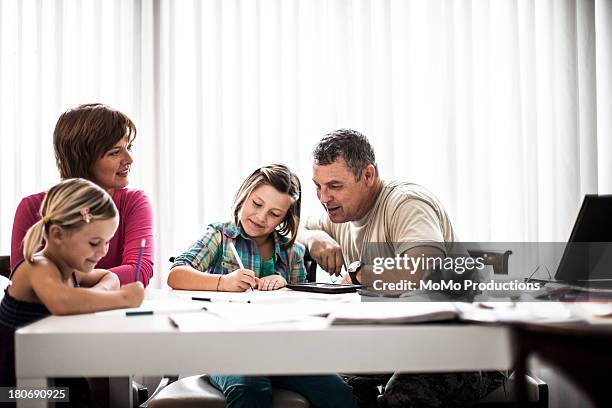 mother and father helping daughters with homework - dad homework stock pictures, royalty-free photos & images