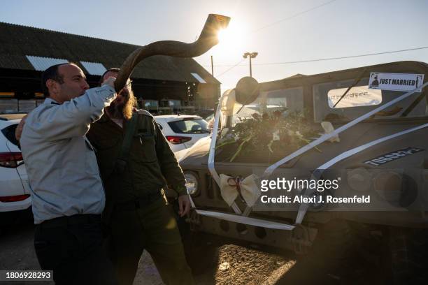 Chief Cantor Lt. Col. Shai Abramson blows a shofar near a hummer covered in wedding decorations ahead of the wedding service for IDF officer Daniel...