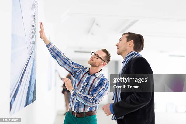 artist showing gallery owner his work - man stand stockfoto's en -beelden