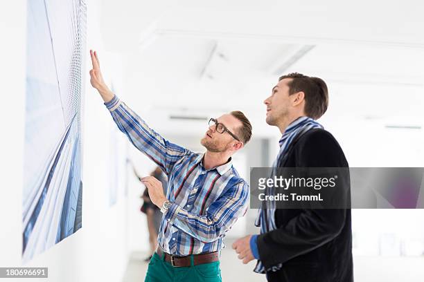 artist showing gallery owner his work - art gallery people stock pictures, royalty-free photos & images