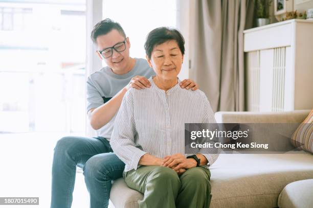 asian man massage his mother at home. - son massage mom stock pictures, royalty-free photos & images