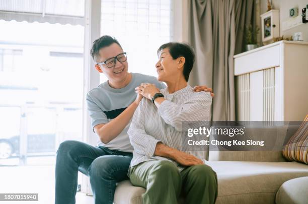 asian man massage his mother at home. - son massage mom stock pictures, royalty-free photos & images