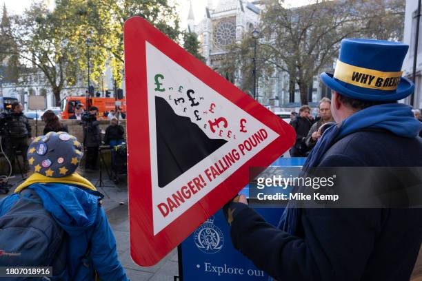 Veteran anti-Brexit protester Steve Bray holds a placard warning sign that warns of the danger of a falling pound on 15th November 2023 in London,...