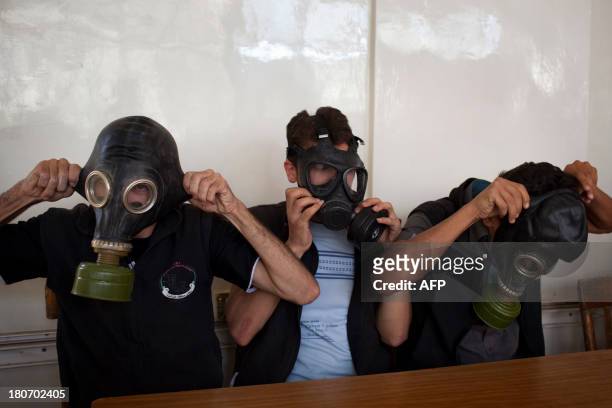 Volunteers put on gas masks during a class on how to respond to a chemical attack, in the northern Syrian city of Aleppo on September 15, 2013. For...