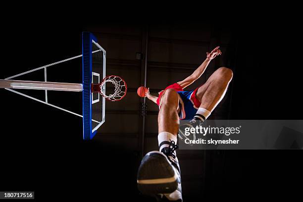 below view of a basketball player slam dunking the ball. - basketball shoe stock pictures, royalty-free photos & images