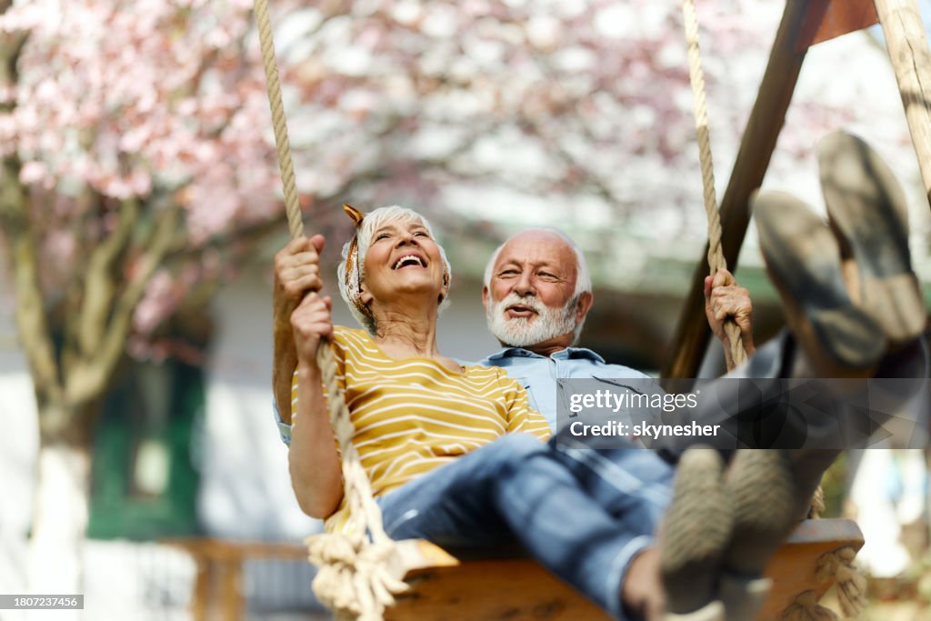 Happy senior couple swinging during spring day in the backyard.