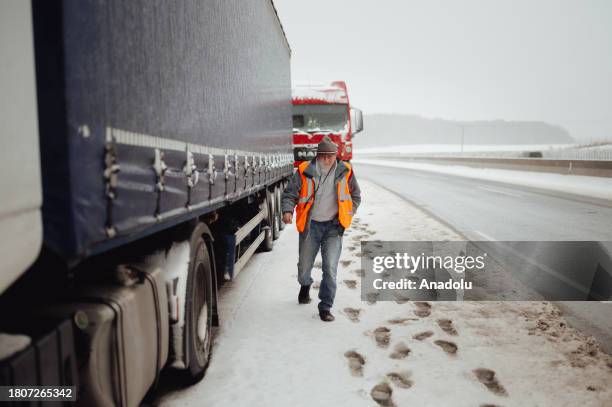 Ukrainian truck driver Vasil Galagovec walks past his snow covered truck that has been standing in a long queue of vehicles for over 10 days now near...