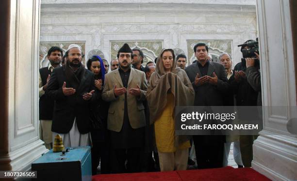 Pakistani former prime minister and opposition leader Benazir Bhutto prays during her visit to a shrine of a Sufi saint on the outskirts of...