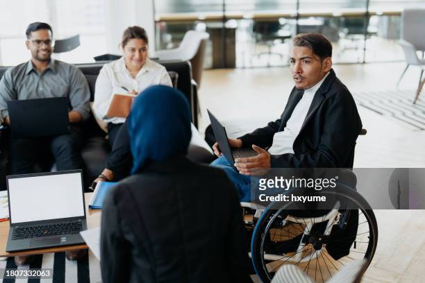disabled business leader on wheelchair giving a speech during team meeting - diversity workplace stock pictures, royalty-free photos & images