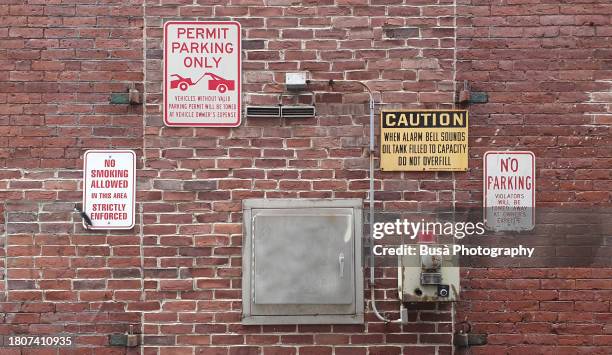 closeup of industrial brick wall with warning signs on it - high voltage sign stock pictures, royalty-free photos & images