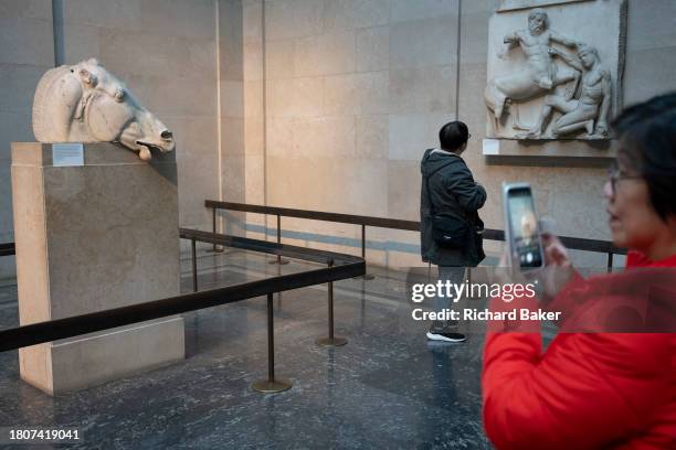 Visitors in London's British Museum admire the horse's head, one of the ancient Greek Parthenon Metopes also knows as the Parthenon Marbles aka Elgin...