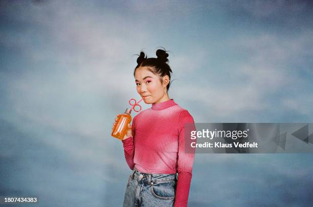 young woman drinking juice from bottle - straw ストックフォトと画像