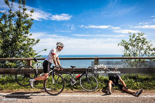 lazy cyclist resting on the road during a bike race - bicycle tire stock pictures, royalty-free photos & images