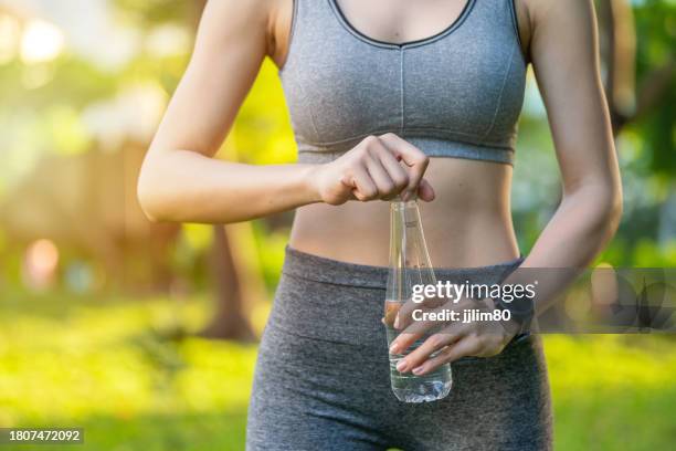 close up body shot of a young asian woman in sportswear wearing smartwatch and holding a bottle of water - open practice stock pictures, royalty-free photos & images