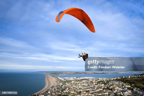 Paraglider flies from Portland Heights with the backdrop of the Jurassic Coast's Chesil beach, on November 22, 2023 in Portland, United Kingdom.