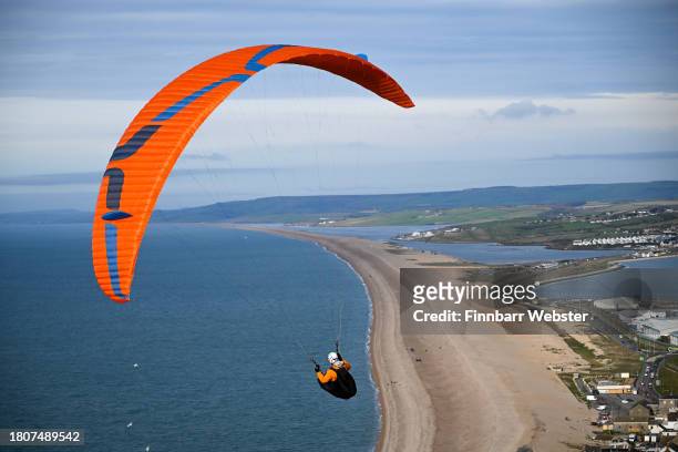 Paraglider flies from Portland Heights with the backdrop of the Jurassic Coast's Chesil beach, on November 22, 2023 in Portland, United Kingdom.