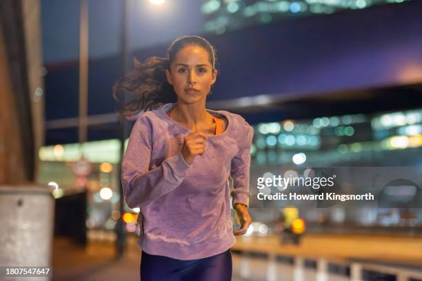 female jogger exercising at night - one mid adult woman only stock pictures, royalty-free photos & images