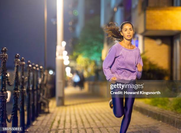 female jogger exercising at night - one mid adult woman only stock pictures, royalty-free photos & images