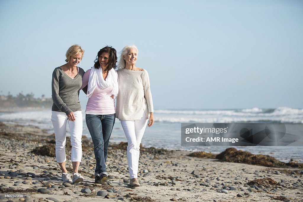 Three women strolling on a beach.