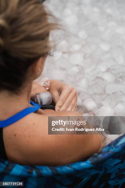woman sitting in an ice bath outside a farm. - eis baden stock-fotos und bilder