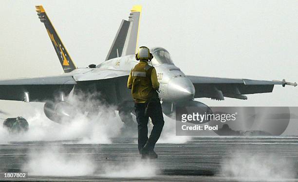 Navy sailor watches an F/A-18 Hornet take off from the USS Abraham Lincoln aircraft carrier February 21, 2003 in the Persian Gulf. The aircraft...