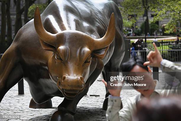 Tourists pose in front of the iconic Wall Street Bull near the New York Stock Exchange on September 16, 2013 in New York City. Five years after the...