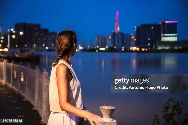 young woman admiring ho chi minh city at sunset. - socialism stock pictures, royalty-free photos & images