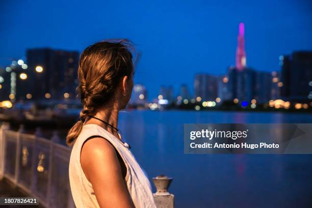 young woman admiring ho chi minh city at sunset. - socialism stock pictures, royalty-free photos & images