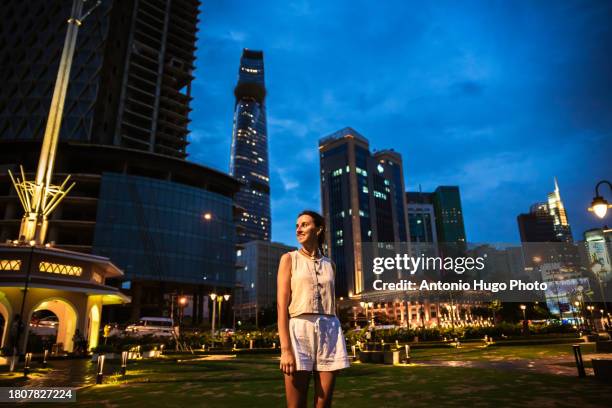 young woman admiring the skyscrapers in ho chi minh city at sunset. - socialism stock pictures, royalty-free photos & images