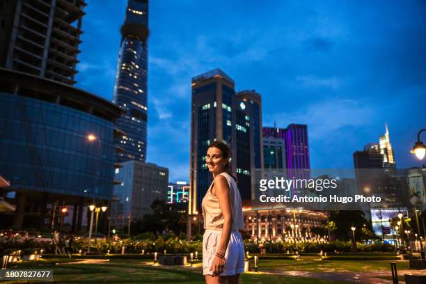 young woman admiring the skyscrapers in ho chi minh city at sunset. - socialism stock pictures, royalty-free photos & images