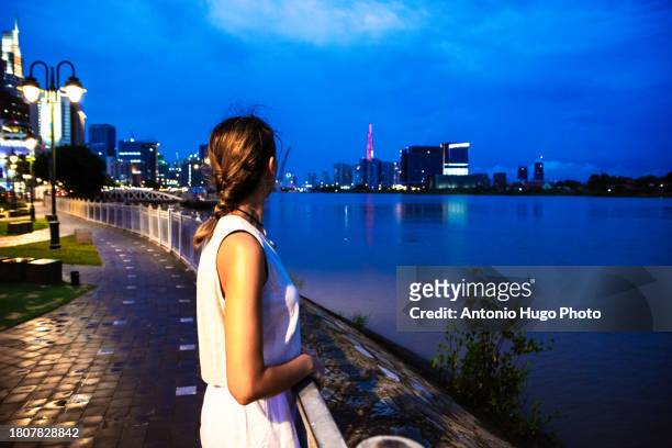 young woman admiring ho chi minh city at sunset. - socialism stock pictures, royalty-free photos & images