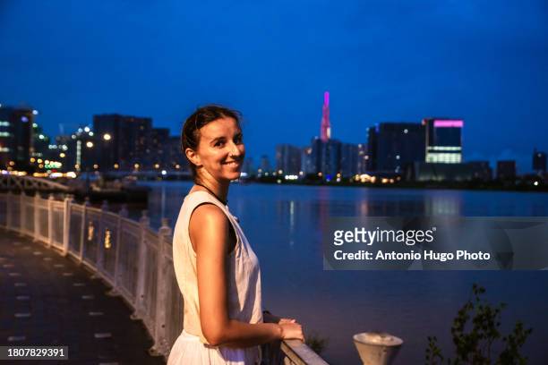 portrait of a smiling woman at sunset in ho chi minh city. in the background the skyscrapers - socialism stock pictures, royalty-free photos & images