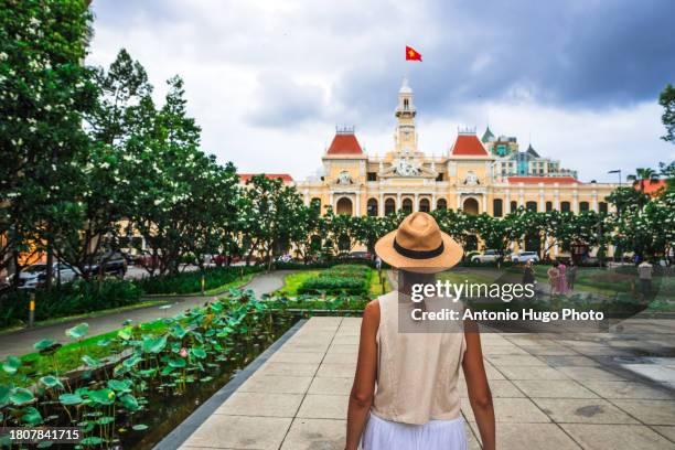 young woman wearing a hat looking at the city hall building in ho chi minh city. - socialism stock pictures, royalty-free photos & images