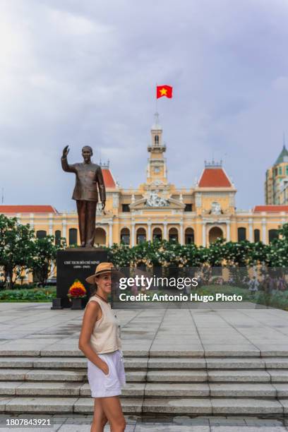 young woman walking in the square where the statue of ho chi minh and the city hall building are located in ho chi minh city. - socialism stock pictures, royalty-free photos & images