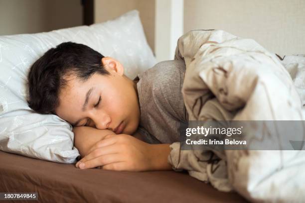 teenage boy boy sleeping in bed, selective focus - boys stock pictures, royalty-free photos & images